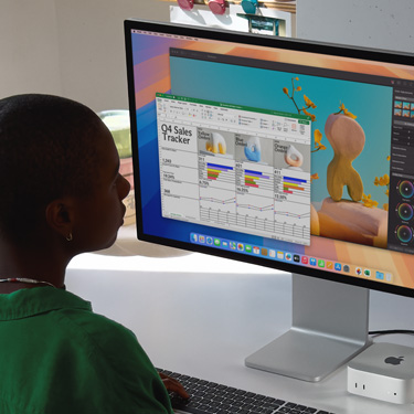 En kvinde sidder ved et arbejdsbord og arbejder i et Excel-ark på en Mac. Excel-arket indeholder salgstal for fjerde kvartal. Bag vinduet med Excel-arket er et Pixelmator Pro-vindue.