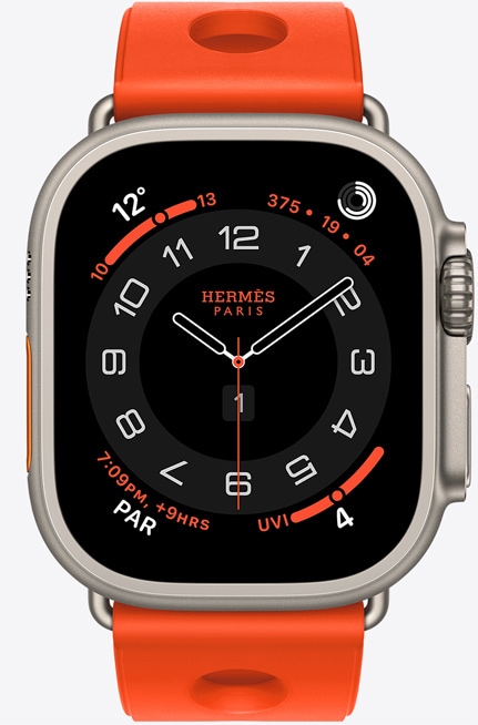 Apple Watch Hermès Ultra 3, Circulaire analog watch face, (hour, minute and second hands, complications: Weather, activity rings, Paris time and UV Index), titanium case, natural color, right side exterior, Digital Crown, raised side button, paired with Scub'H Diving band, orange néon color (bright orange), molded rubber material, circular cutouts centered