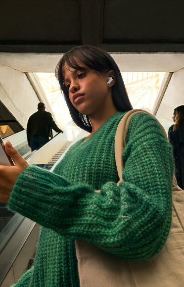 A person wearing AirPods Pro 3 staring into their iPhone