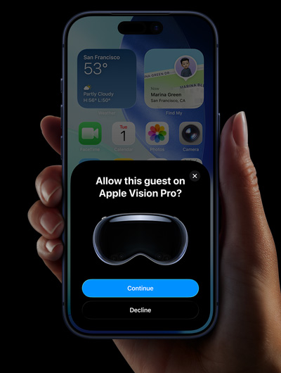A hand holding an iPhone, the iPhone screen displays a window with the message: Allow this guest on Apple Vision Pro with buttons labeled: Continue and Decline