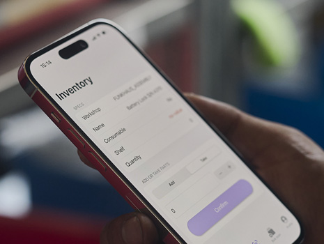 特寫展示手上握著一部 iPhone，螢幕顯示庫存追蹤情況。