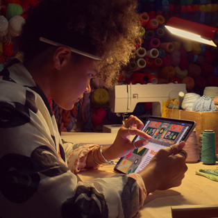 一個人坐在書桌前，用兩隻手指在 iPad 螢幕上放大圖片。