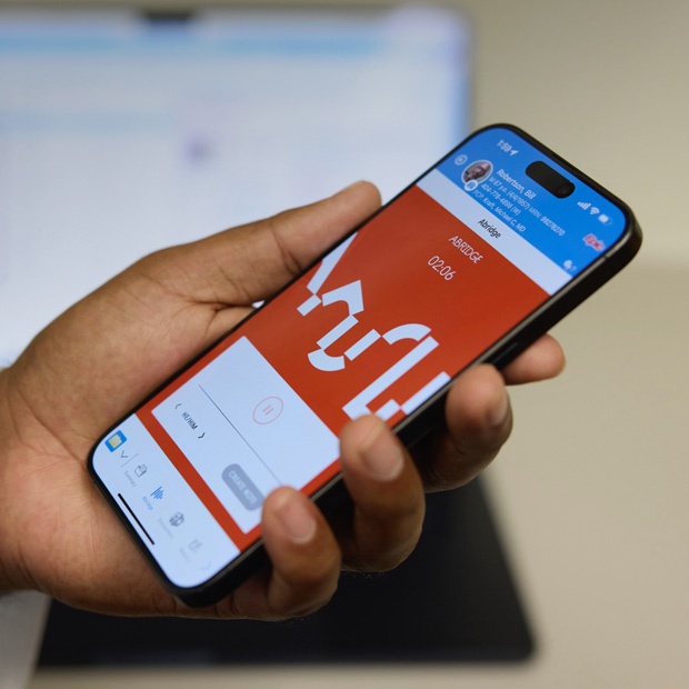 Una mano con un iPhone che mostra l’app Abridge mentre traduce le conversazioni paziente-medico in note cliniche.