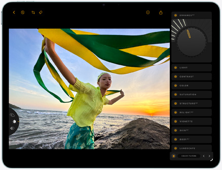 iPad Air, face avant, retouche d’une photo d’une personne tenant un tissu vert et jaune sur une plage au coucher du soleil, avec des outils d’édition visibles sur le côté droit
