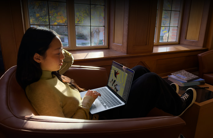 Una persona sentada en una silla usa un MacBook Air